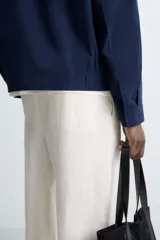 Cazadora bomber azul marino de corte regular fit, confeccionada en tejido de algodón. Presenta cuello solapa, manga larga con puño ajustable de botón, bolsillos de vivo en la cadera, bolsillo interior y bajo con elástico. Cierre frontal con cremallera.