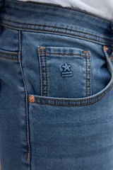 Jean slim fit de color celeste con lavado medio y efecto desgastado sutil. Presenta diseño clásico de cinco bolsillos y cierre frontal con botón y cremallera.