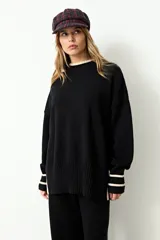 Sweater oversize de tejido rib color negro, con cuello redondo, mangas largas y puños con detalle de rayas en color beige.