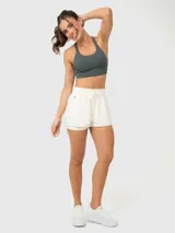 Top deportivo gris con breteles anchos cruzados en la espalda y costuras decorativas en el frente.