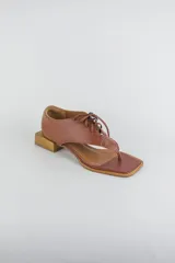 Sandalias de cuero color beige con diseño de ojota acordonada en el empeine, puntera cuadrada y taco bajo cuadrado.