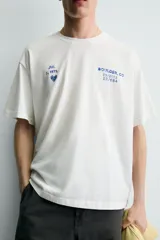 Camiseta de corte relajado con cuello redondo y manga corta. Presenta un diseño con estampados en tono azul con efecto lavado en la parte frontal.