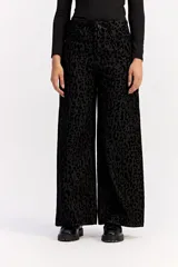 Jean de corte wide leg y tiro medio, confeccionado en algodón con estampado animal print en tonos negros. Presenta un diseño de pierna amplia y cierre frontal con botón y cremallera.