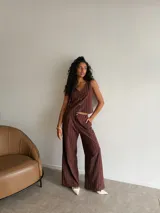 Conjunto de dos piezas compuesto por un chaleco sin mangas con cierre frontal de botones y un pantalón de corte recto y tiro alto. Ambas prendas presentan un diseño a rayas verticales finas en color marrón.