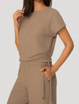 Conjunto de dos piezas compuesto por una remera de manga corta con cuello redondo y frunces laterales ajustables, y un pantalón de corte ancho con cintura elástica y bolsillos laterales.