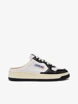 Zapatilla mule de cuero blanco y negro, con cordones y logo de la marca en el lateral.