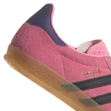 Zapatillas Adidas Gazelle Indoor color rosa con las tres rayas laterales en negro y detalles en azul marino en el talón. Suela de goma color caramelo.