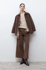 Sweater de punto color beige claro, con escote bote y tejido calado con diseño ondulado. Es de manga larga y corte recto.