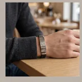 Pulsera de diseño masculino con placa central de acero inoxidable que presenta un grabado de una mano de Hamsa. La estructura se complementa con una banda de goma negra, ofreciendo un estilo moderno y resistente.
