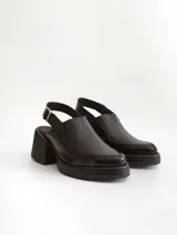 Zapato tipo slingback color negro, con plataforma y taco cuadrado. Presenta una puntera cuadrada y cierre con hebilla metálica en la tira trasera.