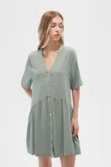 Vestido corto de algodón color verde, con cuello en V, cierre frontal de botones y diseño holgado con falda fruncida.