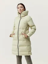 Campera larga tipo puffer de color beige, con acabado mate, cuello alto envolvente y cierre frontal con cremallera. Presenta diseño de bandas acolchadas termoselladas, bolsillos laterales con cierre oculto y relleno vegano.