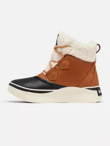 Bota de estilo pato Sorel, confeccionada en cuero impermeable color tostado con forro interior de borrego sintético. Presenta una carcasa de goma vulcanizada negra en la base, entresuela de plataforma en color crema y cierre con cordones.