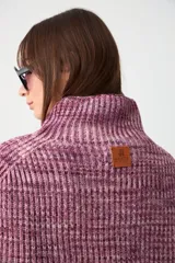 Capita tejida en punto acanalado, con cuello alto y diseño corto tipo poncho.