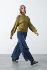 Polera de punto color marrón, con cuello alto y diseño de trenzas verticales en el frente y tejido acanalado en las mangas. Presenta mangas raglán y terminaciones acanaladas en puños y ruedo.