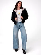 Chaqueta de lona color negro con forro interior de sherpa, cierre frontal con cremallera, capucha y puños elásticos.