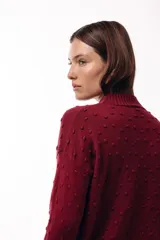 Sweater de tejido de punto con textura de pequeños relieves circulares, cuello redondo y mangas largas. Presenta un calce relajado con puños y ruedo acanalados.