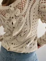 Sweater calado color crudo, de manga larga y cuello redondo.