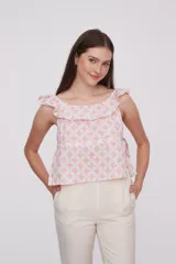 Blusa de algodón con estampado geométrico en tonos rosado y blanco, diseño holgado con escote bote y detalle de volados en los hombros.
