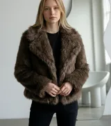 Abrigo corto de piel sintética en color marrón, con solapas amplias y diseño abierto sin cierre frontal.