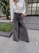 Pantalón de jean estilo wide leg en color gris oscuro con efecto lavado. Presenta un corte de tiro alto, costuras verticales marcadas en el frente y una silueta amplia y fluida.