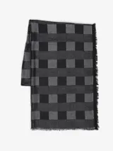 Bufanda de tejido grueso con patrón de cuadros damero en tonos de gris y negro. Presenta flecos deshilachados en los bordes.