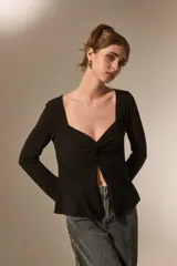 Top de manga larga color negro, con escote cuadrado y detalle de nudo frontal que genera una abertura central. Confeccionado en tejido de poliéster con ajuste al cuerpo.