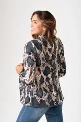 Blazer de poliéster con estampado animal print en tonos grises y beige. Tiene corte ajustado, cuello con solapa y cierre frontal con un botón negro.