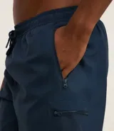 Bermuda deportiva gris oscuro, corte por encima de la rodilla, con cintura elástica y cordón de ajuste. Presenta bolsillos laterales con cierre.