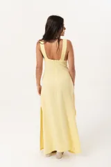 Vestido largo amarillo con escote en V y espalda con tirantes anchos. Confeccionado en lino imperial, con tajos a ambos costados y un diseño que entalla y realza la silueta.