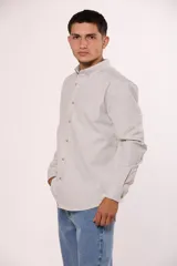 Camisa de manga larga en color gris, confeccionada en algodón, con cuello abotonado y cierre frontal de botones.
