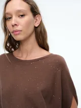 Top de tejido de punto color marrón con detalle de micro lentejuelas brillantes. Presenta un diseño de silueta amplia, cuello redondo y mangas cortas caídas.
