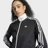 Campera deportiva Adidas Originals, modelo clásico Adicolor Firebird, de color negro con detalles en blanco. Presenta cierre frontal completo, cuello alto tipo embudo, bolsillos laterales con cierre y las icónicas tres tiras blancas en las mangas. El logo del trifolio de Adidas está bordado en el pecho.