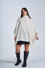 Poncho tejido color beige, con cuello alto y corte asimétrico.