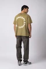 Remera oversize de algodón con efecto lavado gastado, cuello redondo y mangas cortas. Presenta un diseño circular estampado en el pecho con el texto VCP CONCEPT STUDIO.