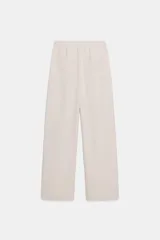 Pantalón de tiro medio color beige, de pierna ancha y corte recto. Cuenta con cintura elástica ajustable con cordones y bolsillos frontales.