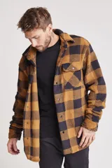 Camisa de abrigo de tela tipo borreguito a cuadros color marrón y negro, con cuello clásico, cierre frontal con botones a presión, bolsillo de parche en el pecho y puños abotonados.