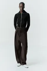 Chaqueta de felpa negra con cuello solapa, manga larga con puño, bolsillos de plastrón en el delantero y cierre frontal con cremallera.