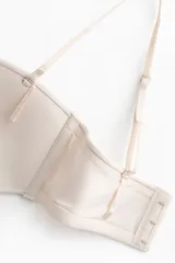 Soutien strapless de microfibra en color beige con copas acolchadas, tirantes ajustables y desmontables, y cierre posterior de corchetes.