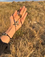 Collar tipo gargantilla con dije de flor metálica de acabado brillante, suspendido de un cordón doble de seda natural teñido a mano en color rojo.