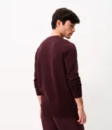 Suéter de punto para hombre color bordó, con textura acanalada horizontal, cuello redondo y mangas largas con puños ajustados.