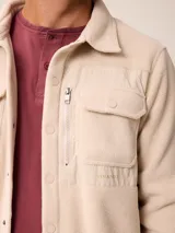 Sobrecamisa de polar azul marino con cierre frontal de botones a presión. Presenta bolsillos frontales con solapa, uno de ellos con cierre de cremallera adicional y detalles en contraste de material técnico.