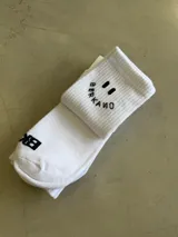 Medias blancas largas con elástico acanalado, diseño de carita feliz y la palabra "BERKANO" en el puño.