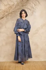 Conjunto de dos piezas compuesto por una camisa de manga larga con volados frontales y cierre de botones, y una falda larga a juego. Ambas prendas presentan un estampado floral en tonos azulados.