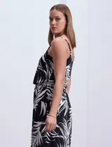 Vestido largo negro con estampado de hojas blancas, escote redondo, breteles finos regulables con detalle de cadena dorada.