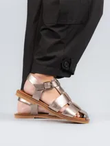 Sandalias tipo pescador con diseño de tiras anchas entrelazadas, confeccionadas en cuero color plateado. Presentan cierre mediante hebilla metálica lateral, plantilla de cuero y suela plana de goma.