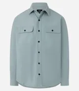 Camisa de manga larga confeccionada en sarga de algodón color verde menta, con cuello inglés y cierre frontal de botones negros. Presenta dos bolsillos de parche con solapa en el pecho y puños con botones.