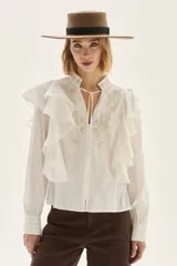 Blusa de algodón color blanco con volados frontales, cuello mao con lazos y detalles bordados en el pecho.