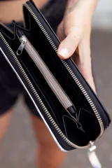 Billetera grande de cuero charol negro con borde superior blanco y cierre con cremallera.