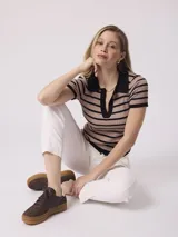 Remera tejida a rayas horizontales color beige y negro, con cuello tipo polo y mangas cortas.